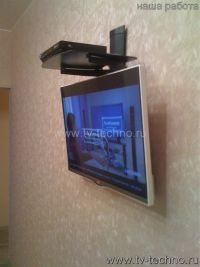 Телевизор на стене с полкой сверху.